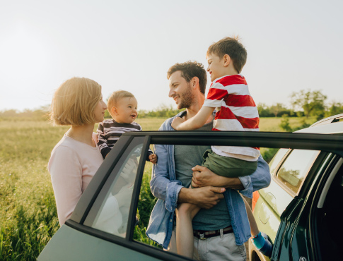 Family of four at their car door