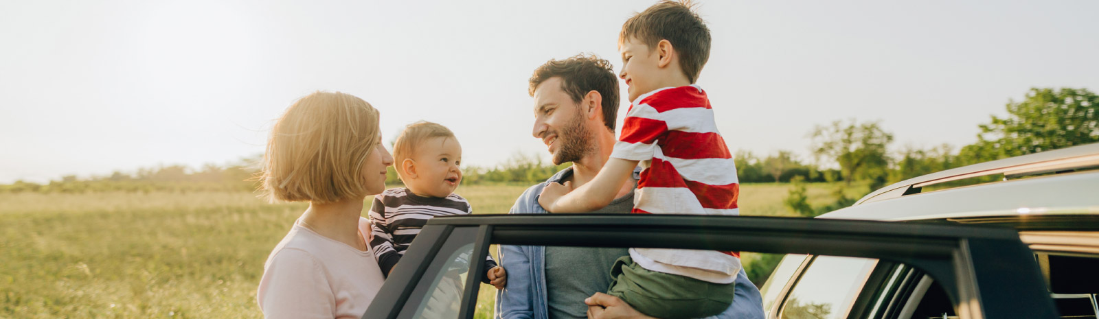 Family of four at their car door