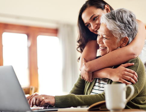 One young woman and a mature woman smiling and looking at computer